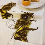 Detail of honey bee design on linen tea towel